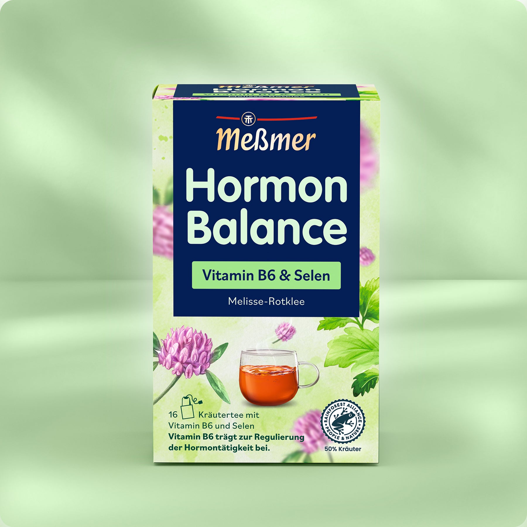 Dose Meßmer DE Hormon Balance Kräutertee mit Vitamin B6 und Selen, mit Melisse, Rotklee und Kräutern neben einer Glastasse mit Tee auf grünem Hintergrund. Der Text betont die Unterstützung der Hormonregulation.