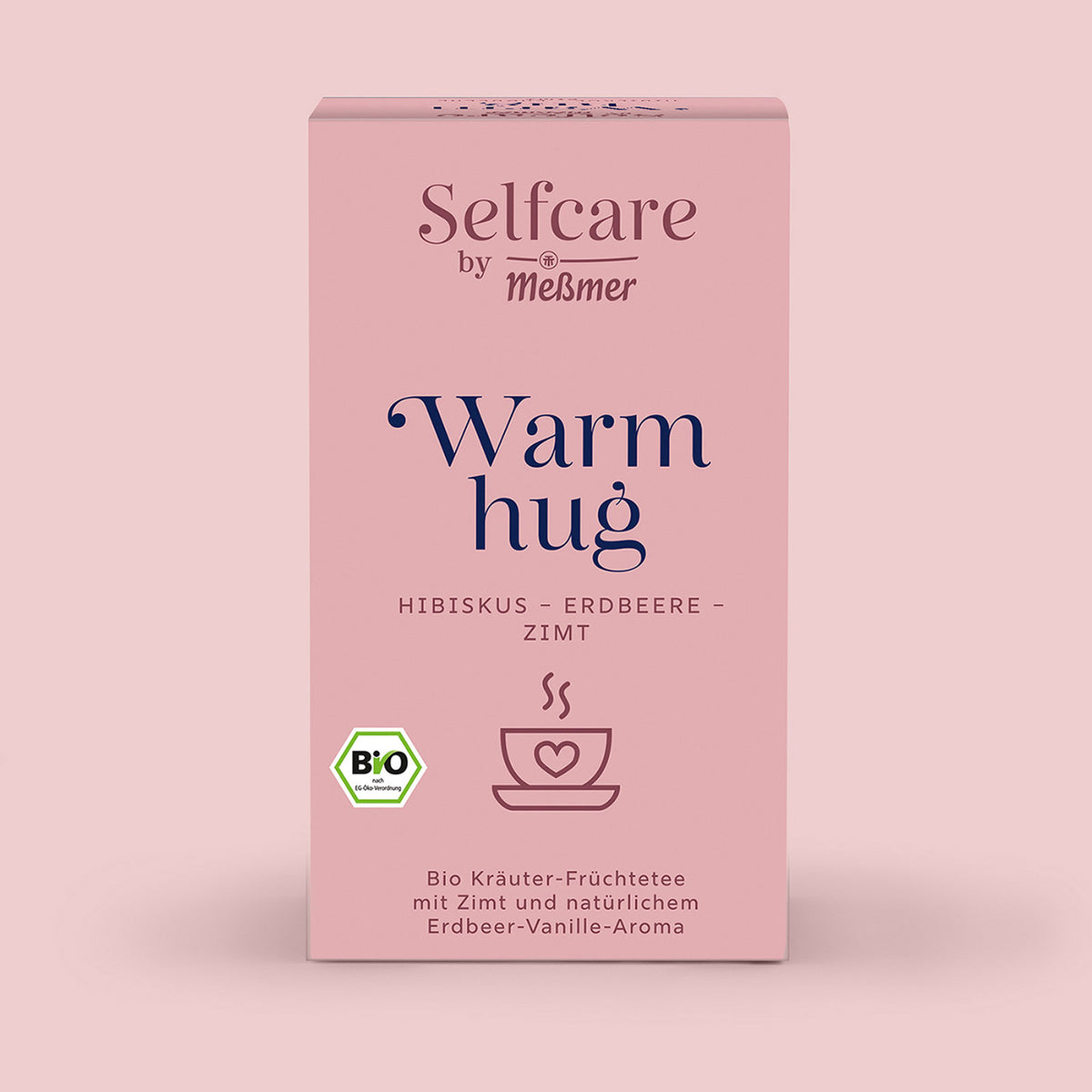 Verpackung von Bio Warm Hug Kräuter-Früchtetee mit Bio-Siegel, Hinweis auf Hibiskus, Erdbeere, Zimt und Vanille-Aroma, präsentiert auf zartrosa Hintergrund in entspannter Atmosphäre.